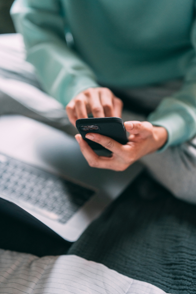 Send email, SMS texts, letters, etc. Person on their phone above an open laptop